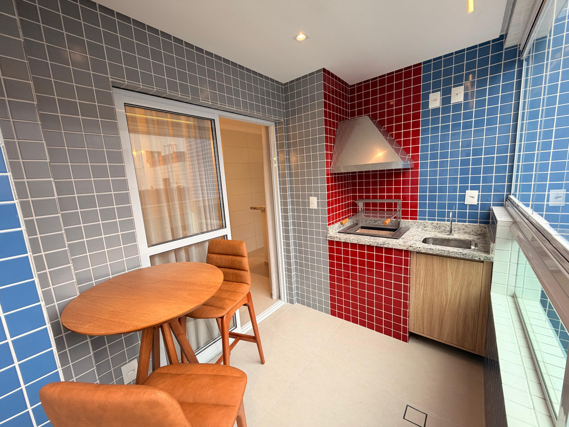 Varanda gourmet com churrasqueira a carvão do apartamento decorado